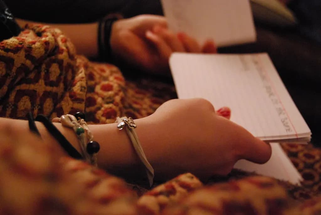 A student's hands holding a stack of handwritten index-card flashcards while revising