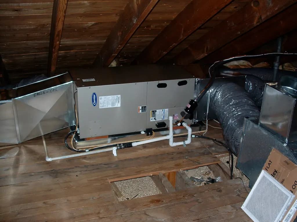 A newly installed horizontal air handler in a residential attic with flexible ductwork and condensate piping