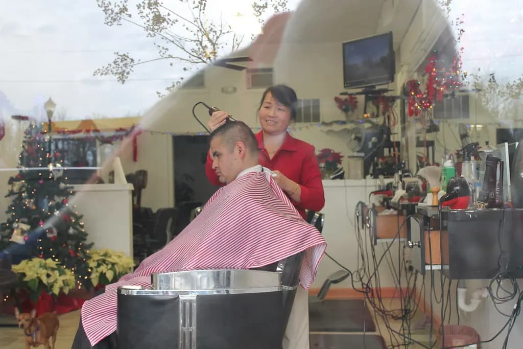 A barber cutting a customer's hair inside a neighborhood barber shop in Hyattsville, Maryland