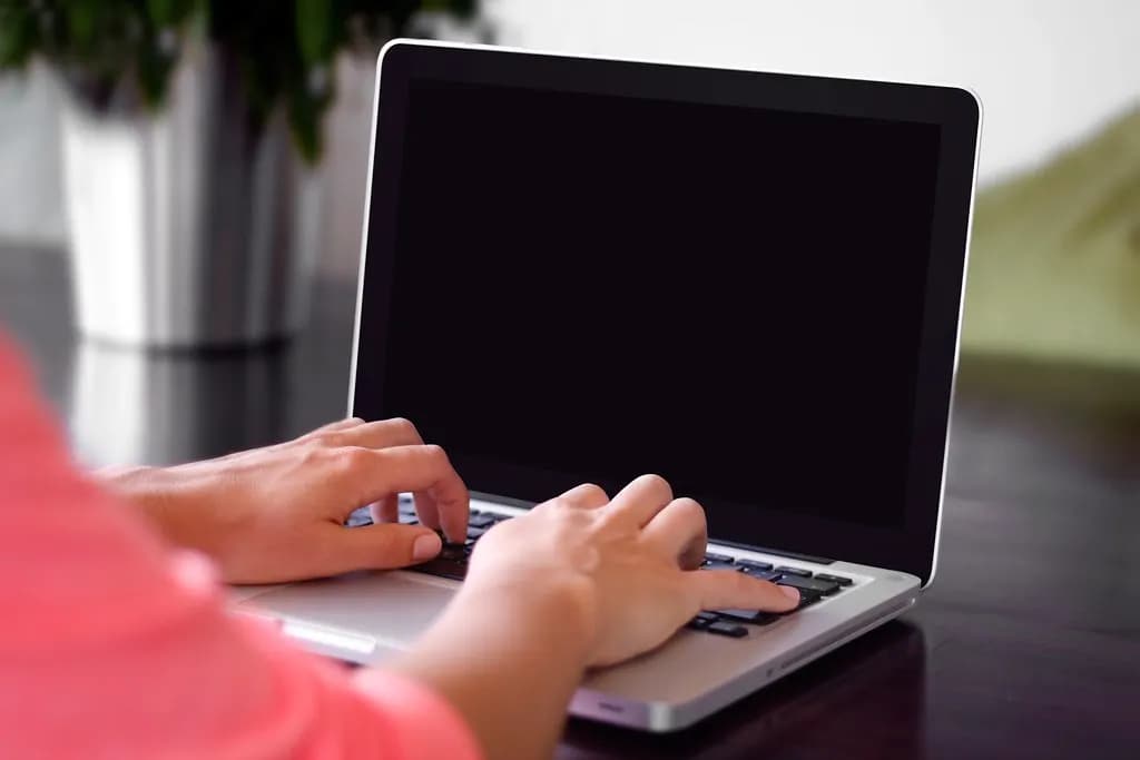 Freelancer typing on a laptop at a desk at home