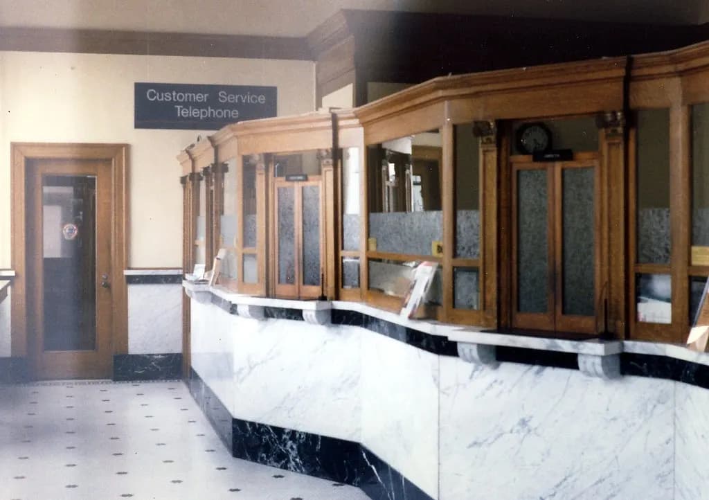 Historic bank lobby with wooden teller windows above a marble counter