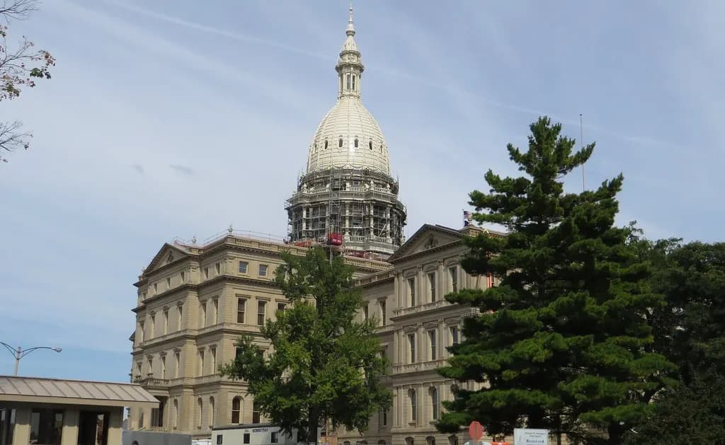 The Michigan State Capitol in Lansing with its white dome above a tree-lined lawn