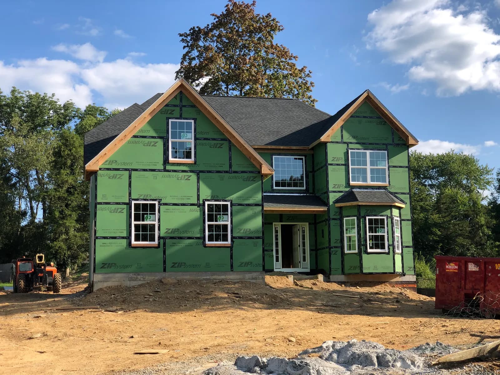 New two-story house under construction with green sheathing and a finished roof