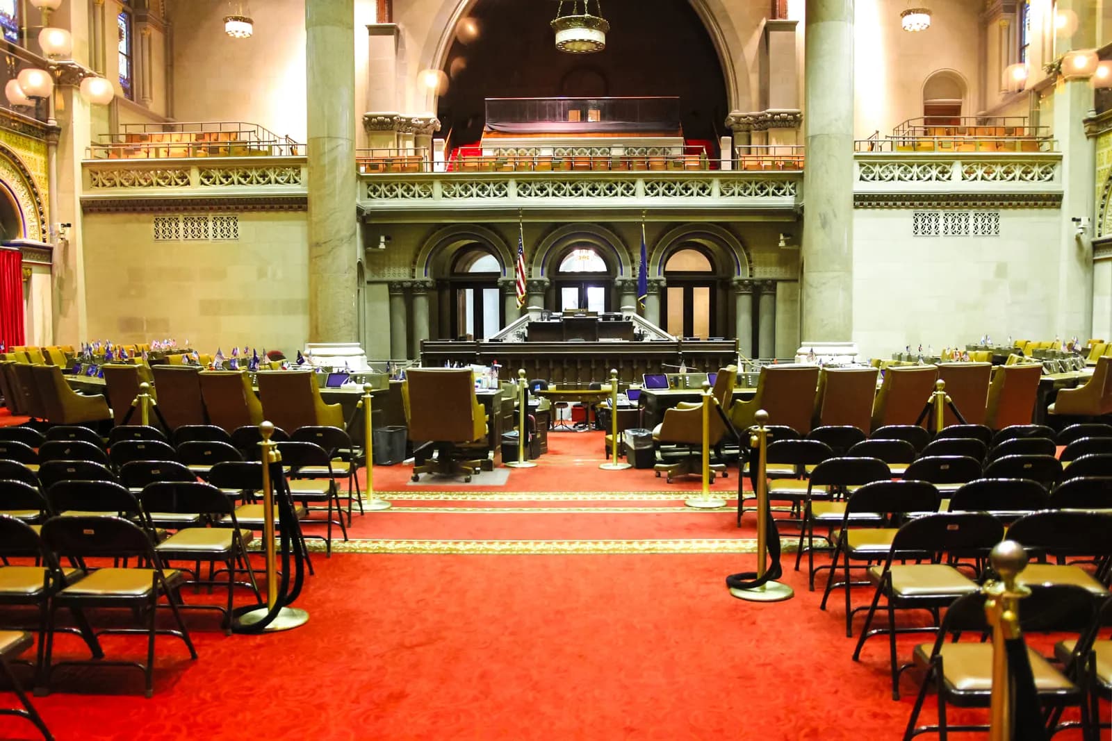 The red-carpeted Assembly Chamber inside the New York State Capitol in Albany with rows of members' chairs
