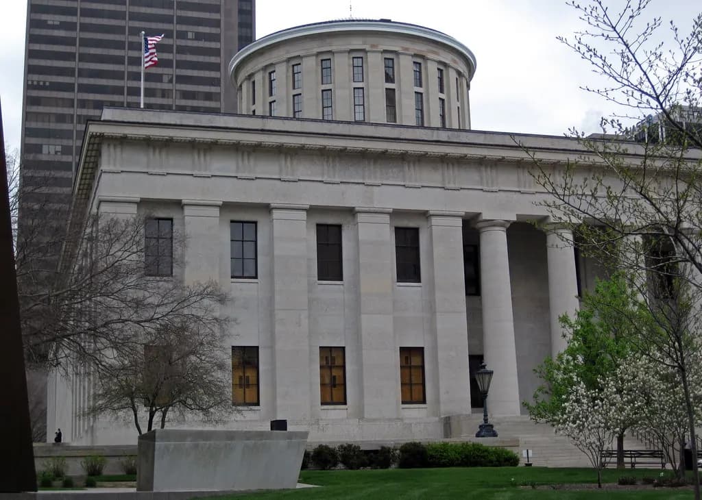 The columned Ohio Statehouse in downtown Columbus with office towers behind it