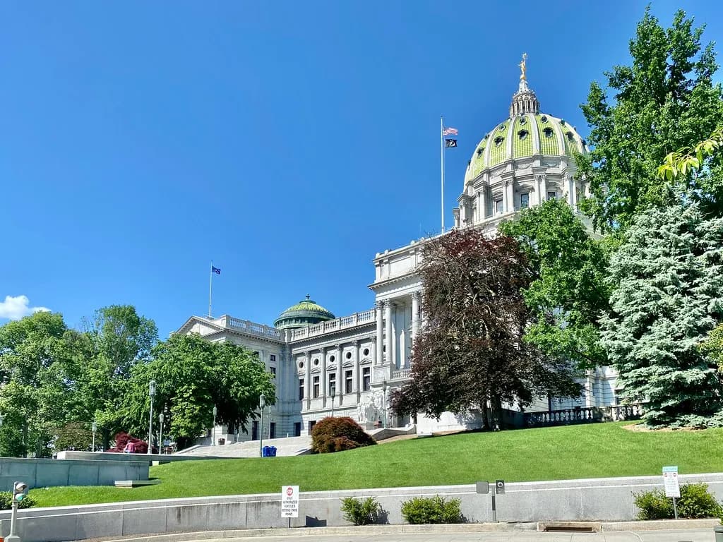 The green-domed Pennsylvania State Capitol in Harrisburg above a sloping lawn and trees