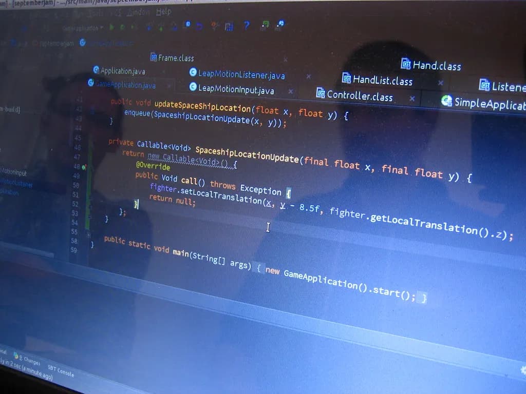 Software developer reflected in a monitor showing lines of code