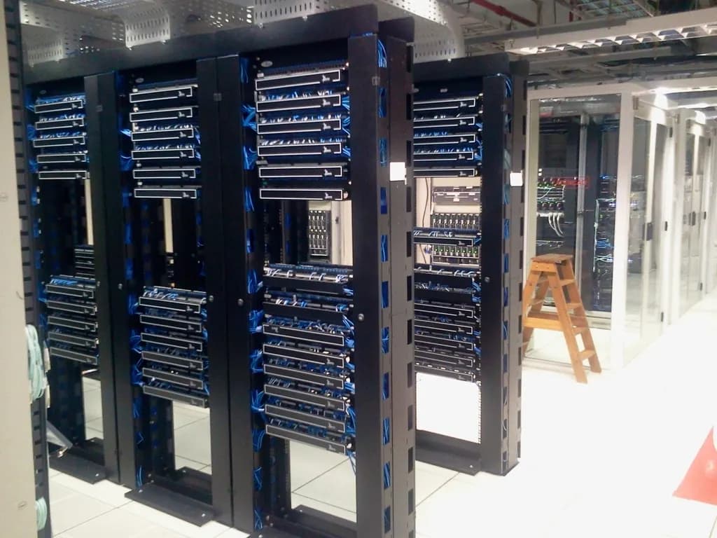 Rows of black server racks with blue network cabling in a data center