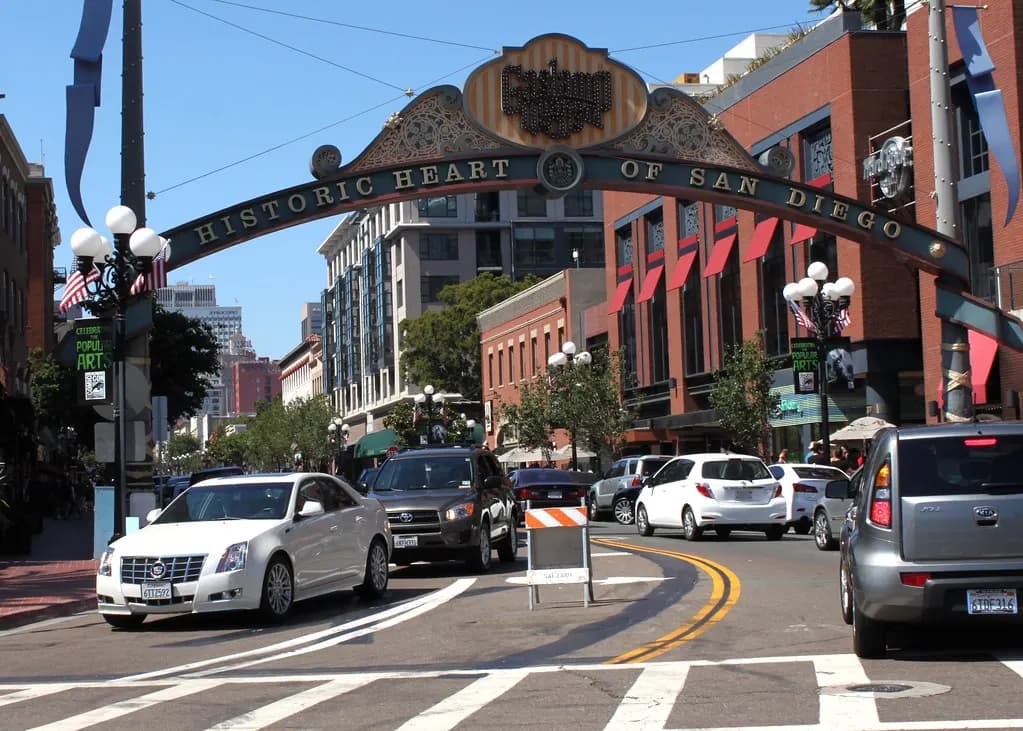 The Gaslamp Quarter arch over Fifth Avenue in downtown San Diego with traffic and shopfronts