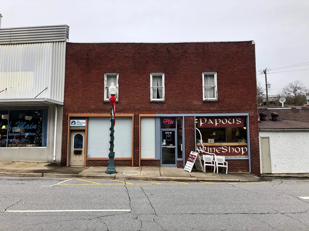 Brick main-street storefronts in Sylva, North Carolina, including an antiques shop and a wine shop with an open sign
