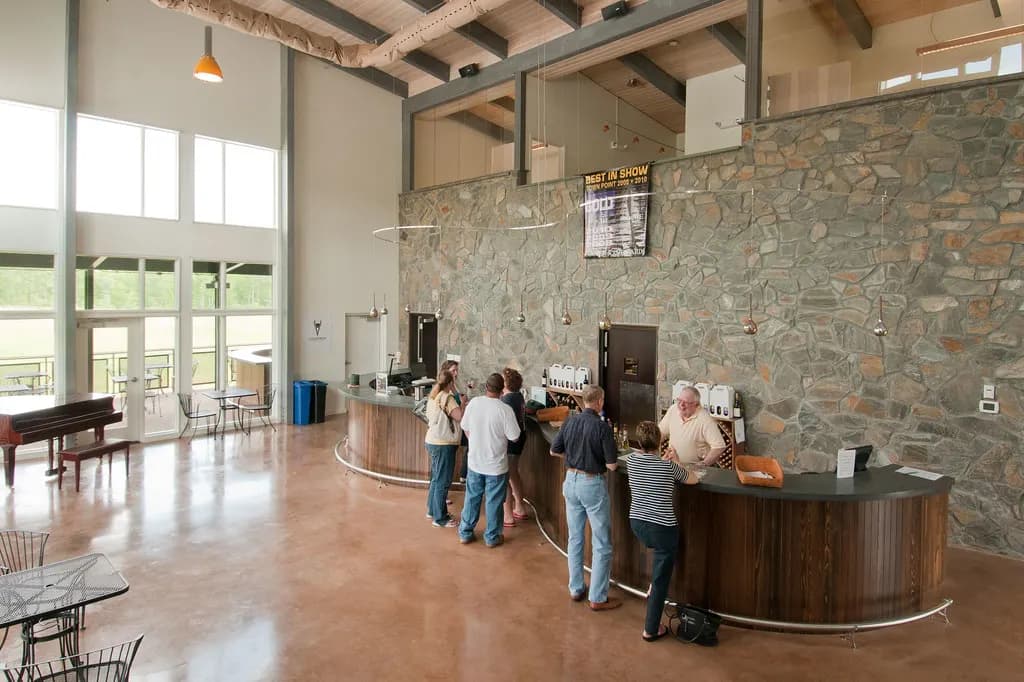 Customers at the counter of a small winery tasting room with stone walls and high windows