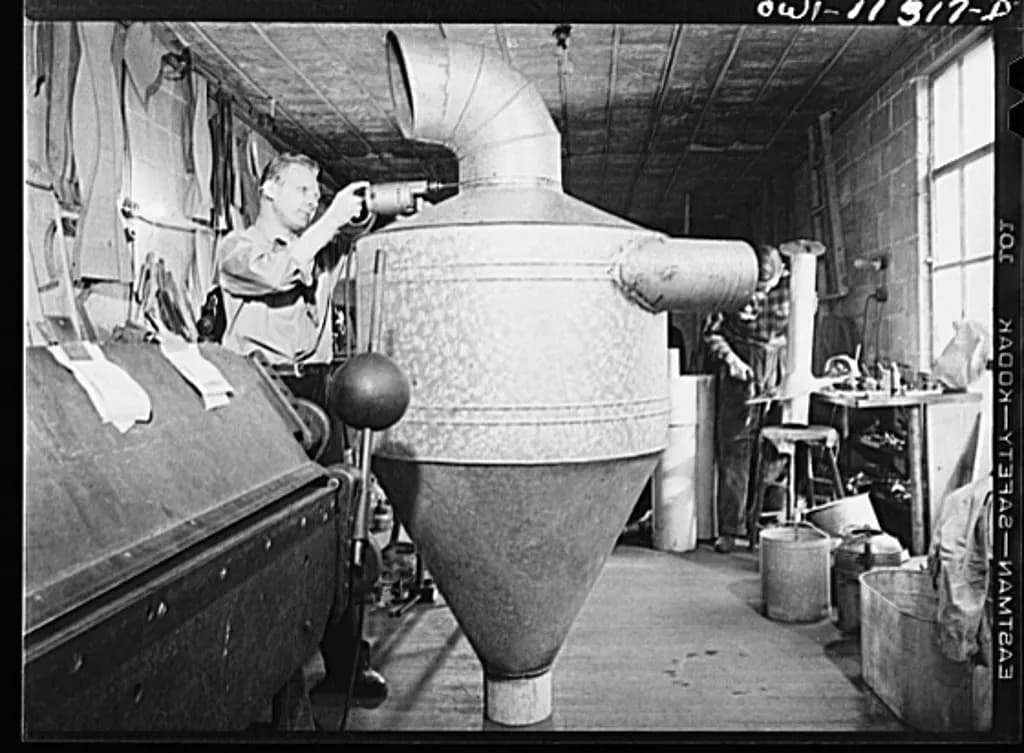 Workers drilling and assembling sheet-metal equipment in the machine shop behind a small-town hardware store, 1942