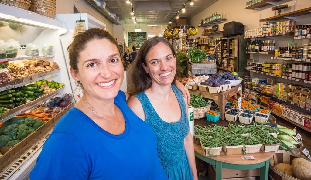 Two co-owners standing among produce displays and shelves in a small neighborhood grocery store in Washington, DC