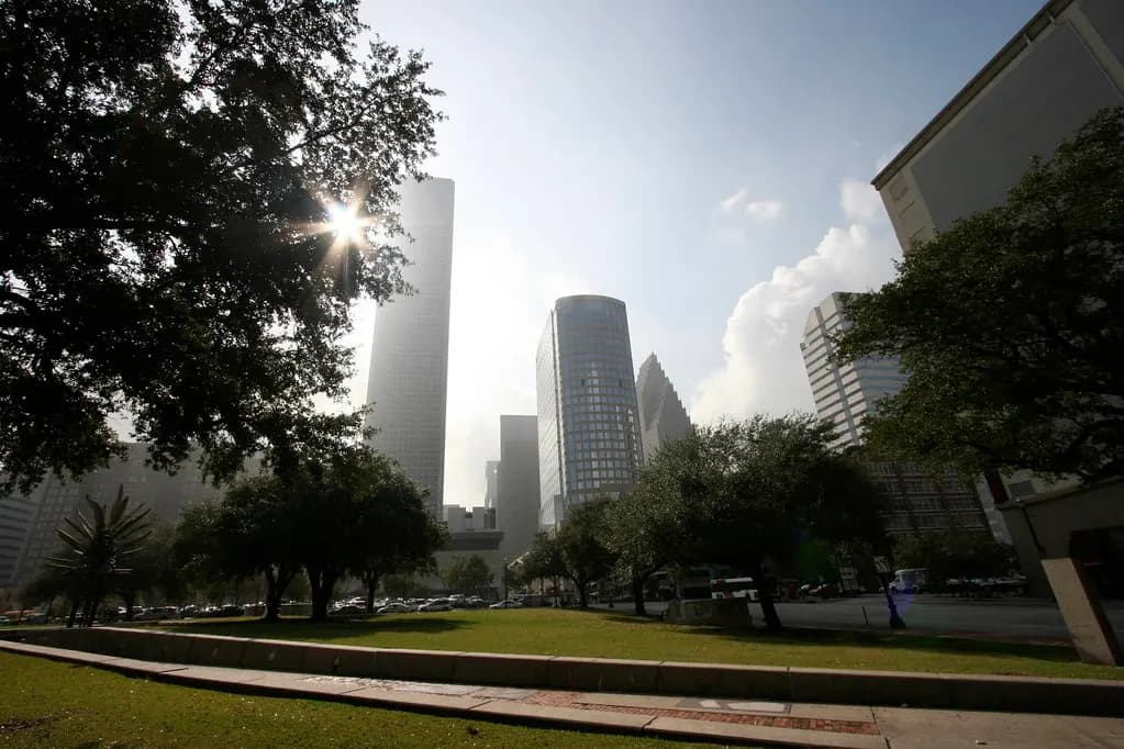 Downtown Houston towers rising behind the trees and lawn of Market Square Park