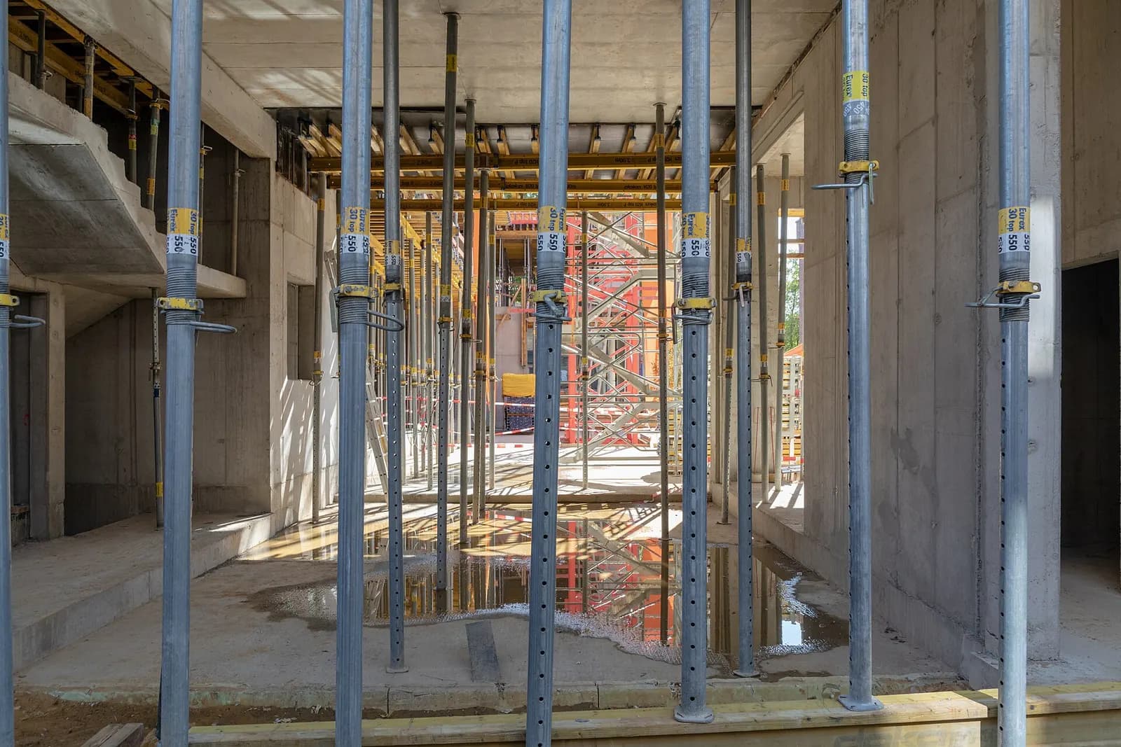 Steel shoring props holding up a concrete floor slab inside a building under construction