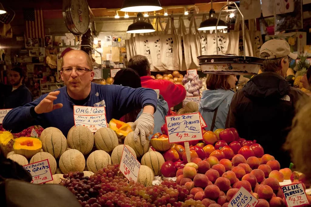A vendor arranging produce at a stall in Pike Place Market, Seattle