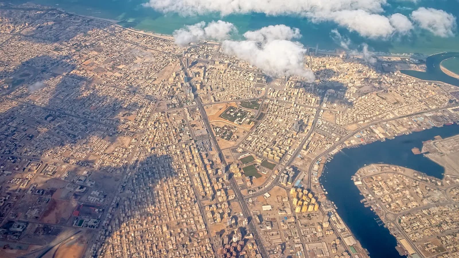 Aerial view of Ajman city with its dense street grid, the creek and port area on the right and the Gulf coast at the top