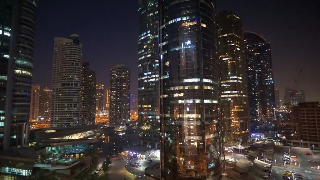 Jumeirah Lakes Towers in Dubai lit up at night, reflected in the lake