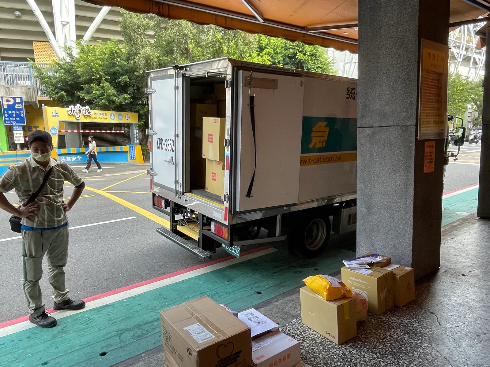 Courier staff sorting customer parcels on the pavement before last-mile home delivery