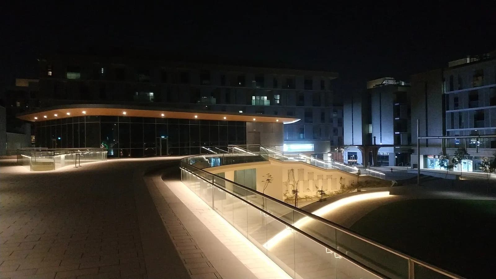 Low-rise buildings and a lit pedestrian plaza in Masdar City, Abu Dhabi, at night