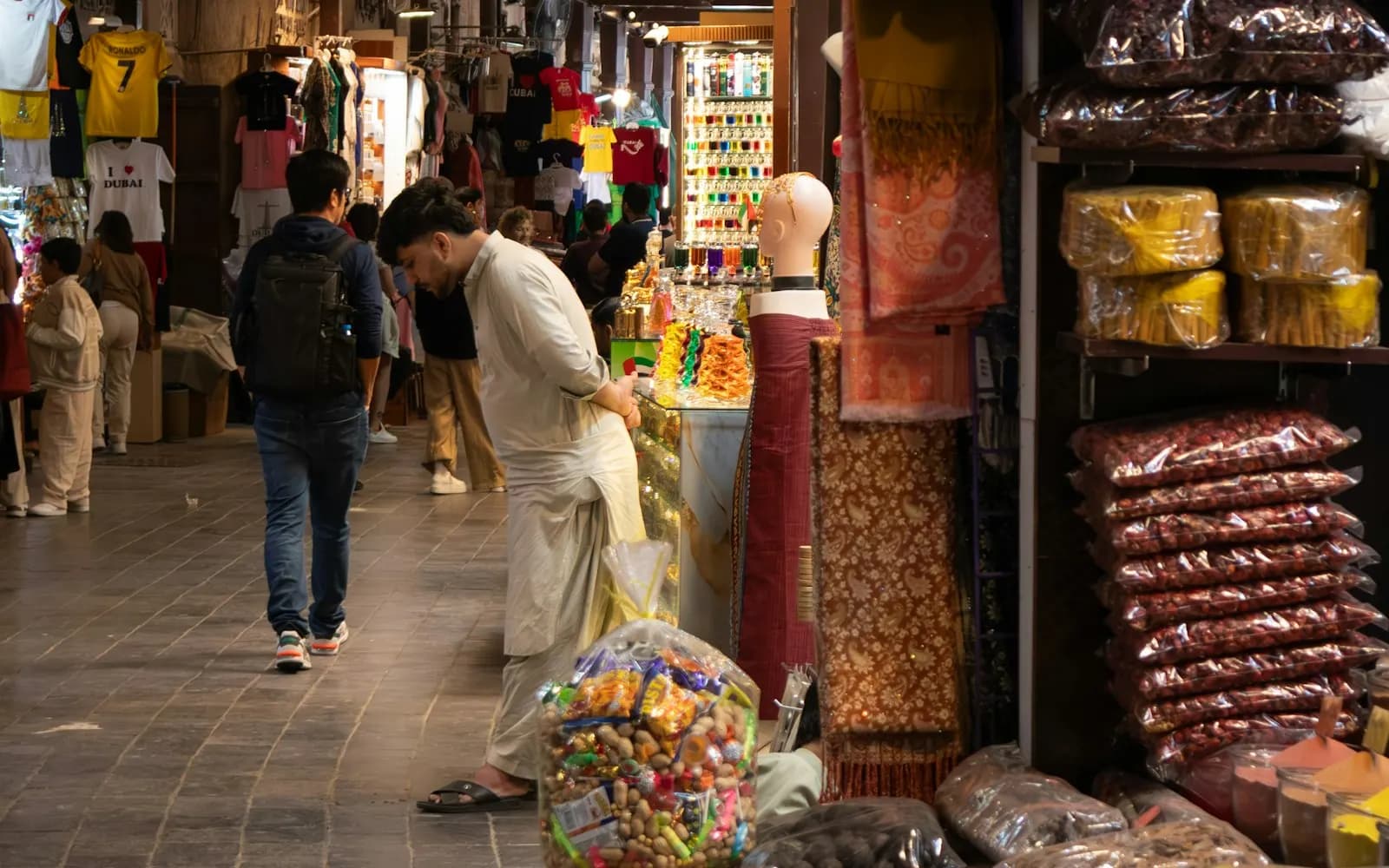 Shopper browsing sacks of spices and dried herbs at a trader's stall in a Dubai souk