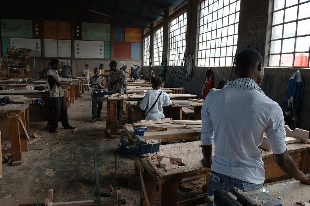 Apprentice carpenters working at benches in a large joinery workshop