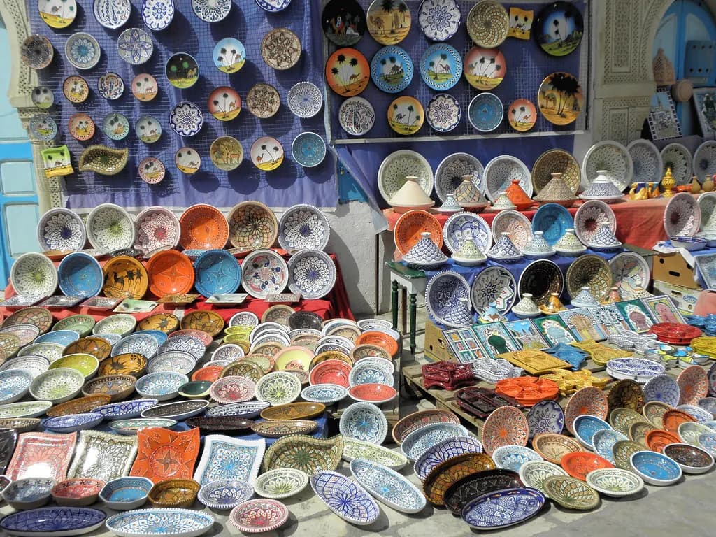 Hand-painted ceramic plates and bowls laid out for sale at a market stall