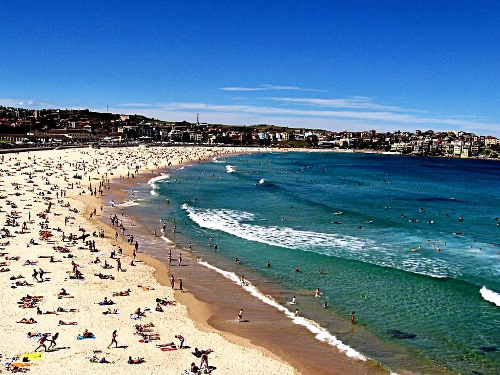Crowded Bondi Beach in Sydney on a clear summer day with surf rolling in