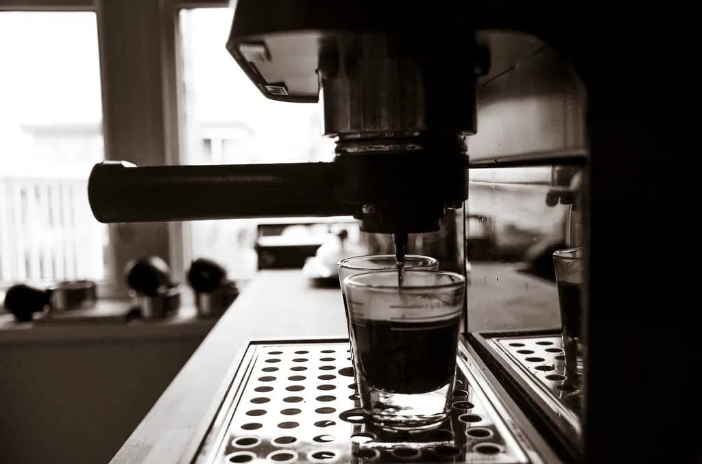 Espresso pouring from a commercial coffee machine into a glass