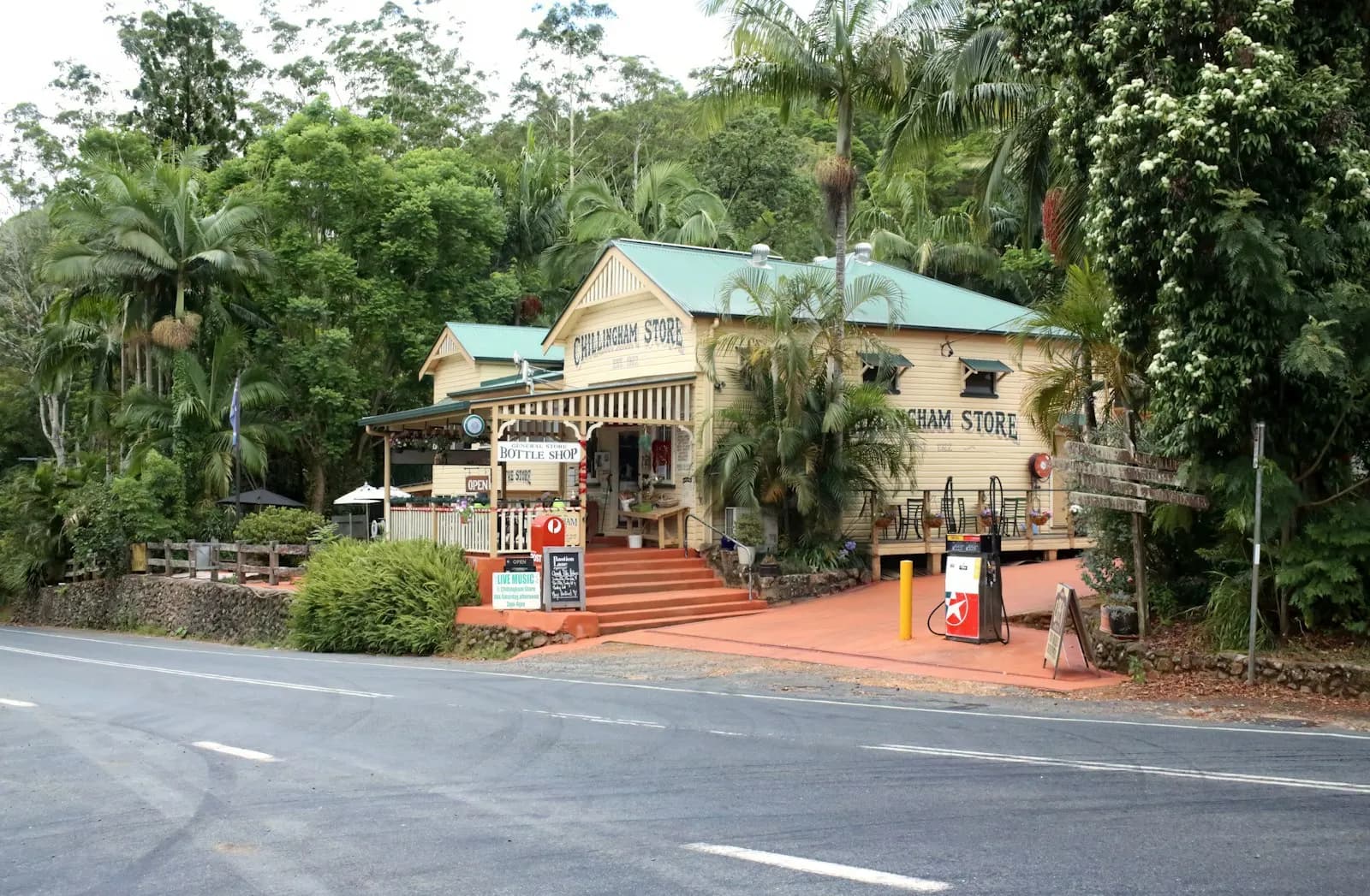 Timber general store with signage and a fuel bowser beside a rainforest road in Chillingham, New South Wales