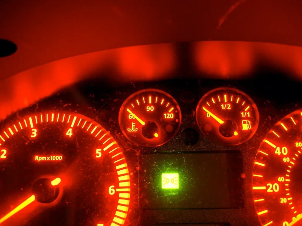 Illuminated car dashboard gauges showing speed and engine revs at night