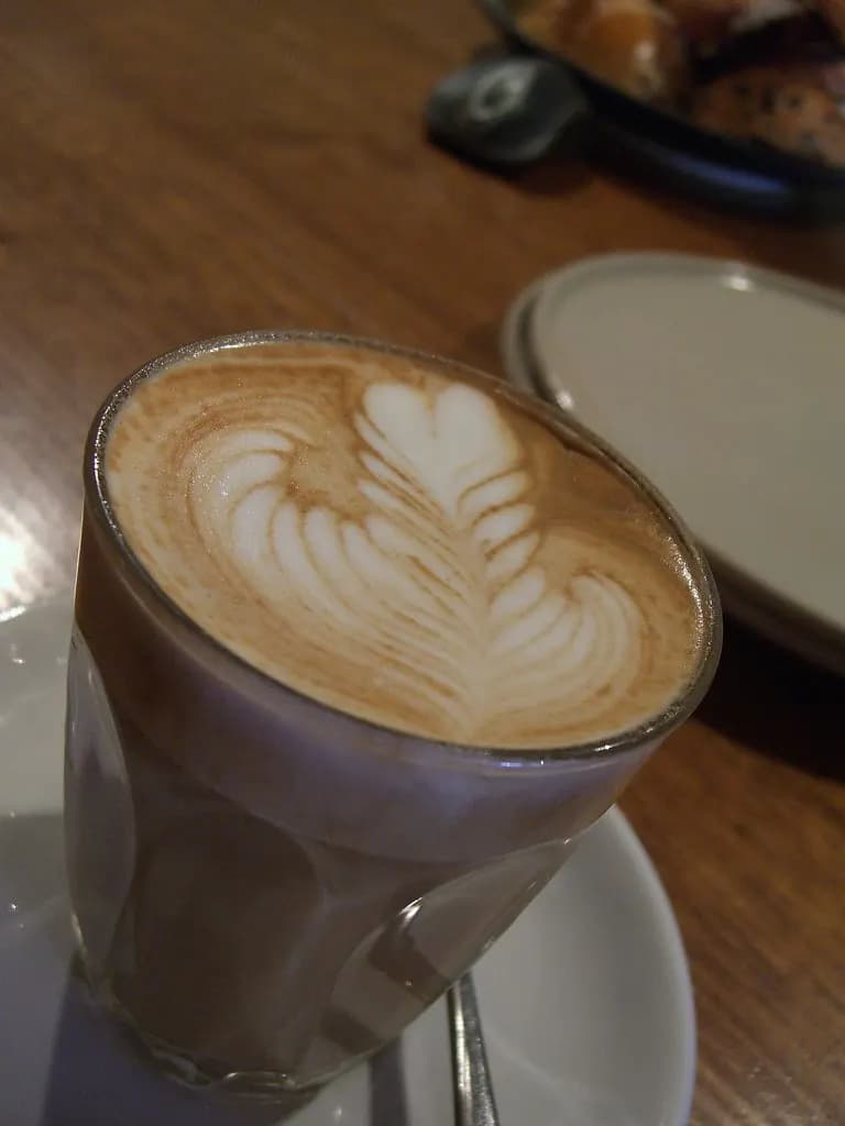 Caffe latte with leaf-pattern latte art on a cafe table in Melbourne
