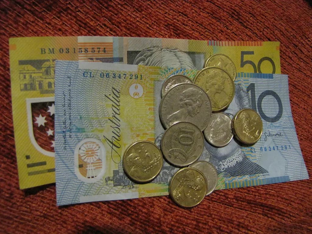Australian fifty- and ten-dollar notes with a pile of coins on a red cloth