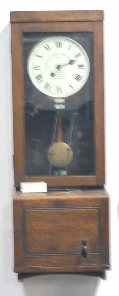 Antique oak-cased employee time clock with a punch-card slot below the dial