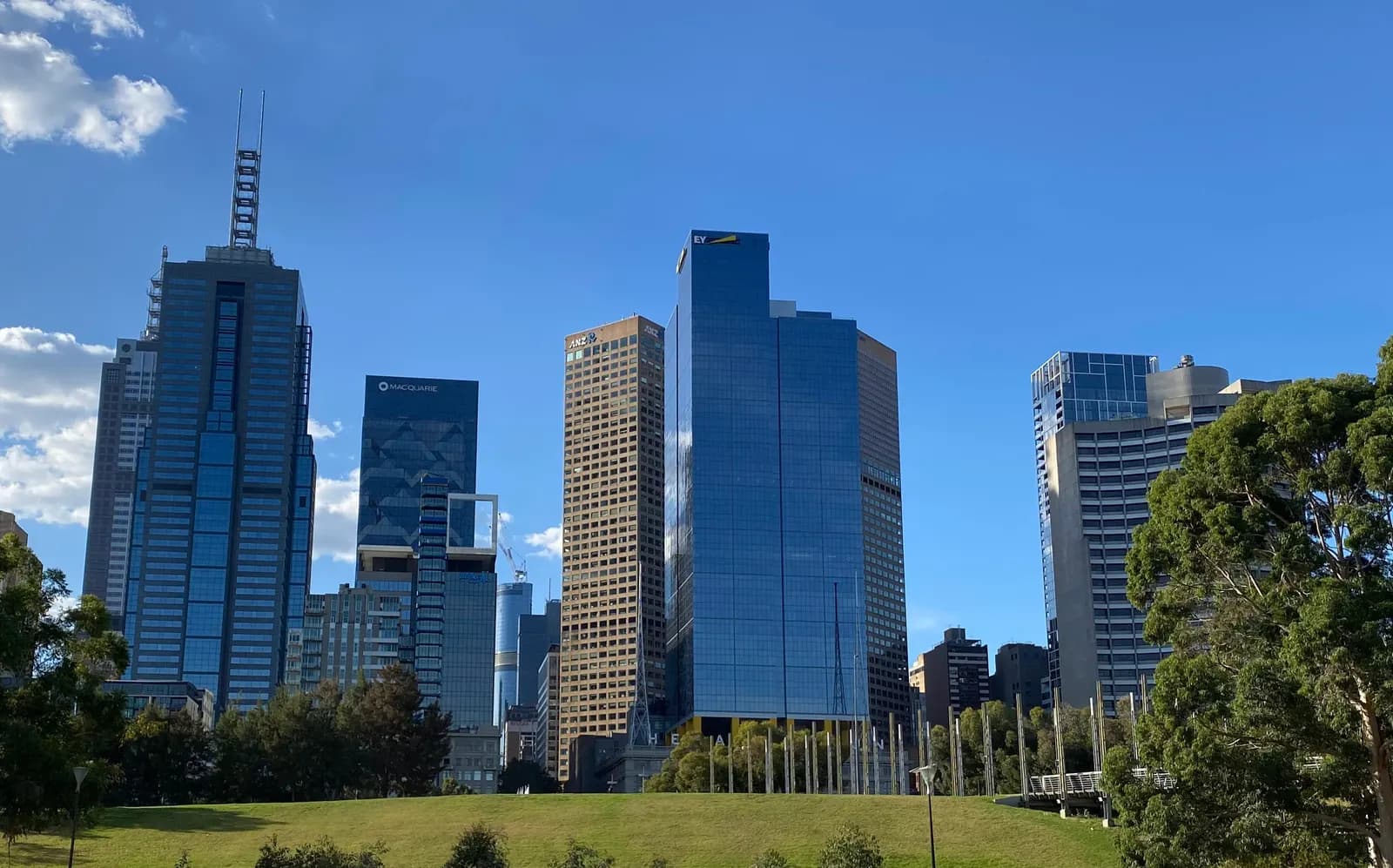Glass office towers of Melbourne's central business district under a blue sky, seen from Birrarung Marr