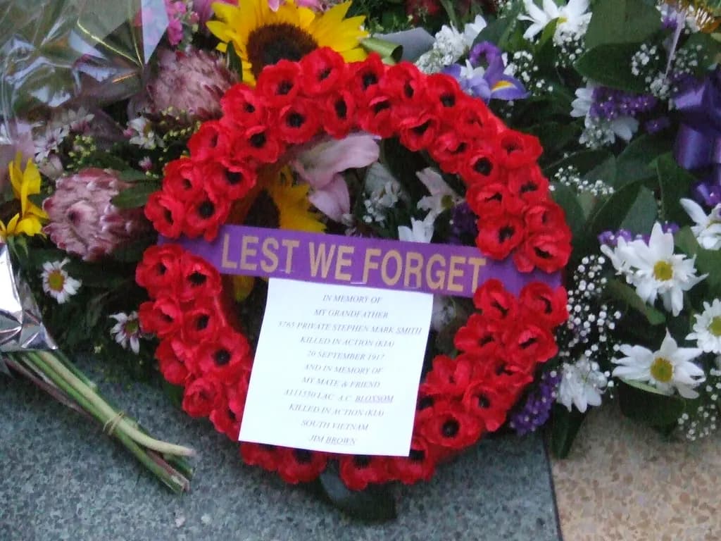 A red poppy wreath reading Lest We Forget laid among flowers at an Anzac Day dawn service in Brisbane