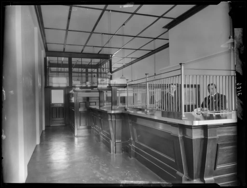 Interior of a Commercial Bank of Australia branch around 1930, with timber counters and tellers behind grilles