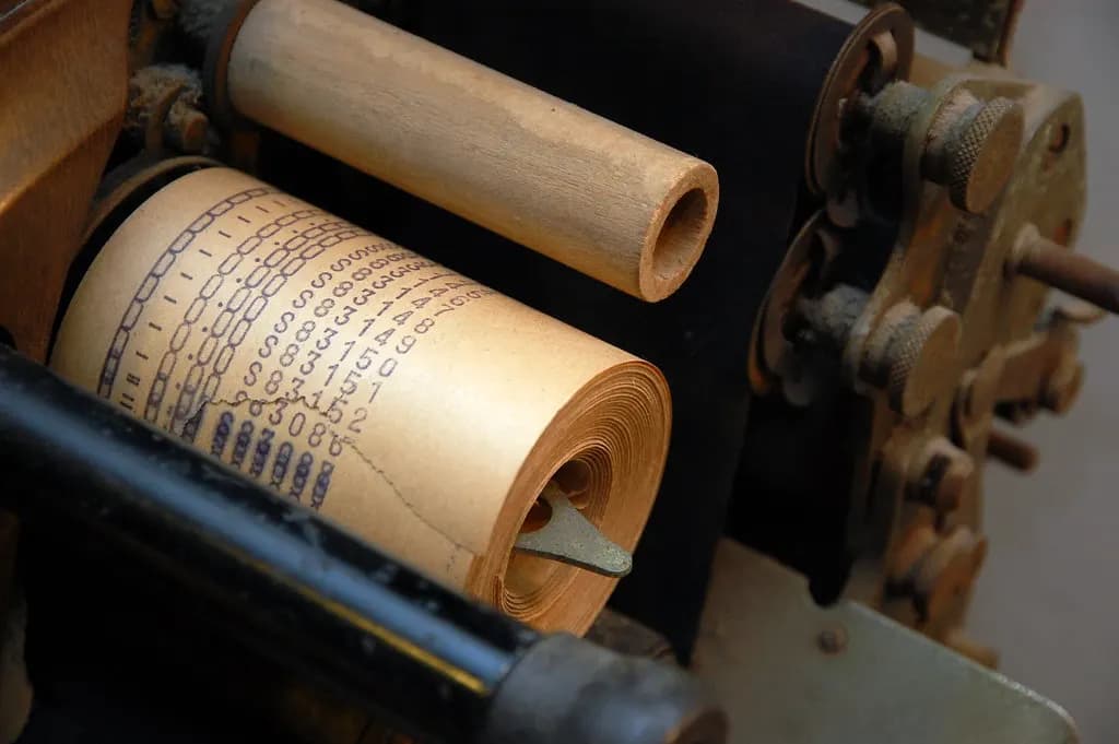 Paper roll of printed receipts feeding through an old cash register mechanism