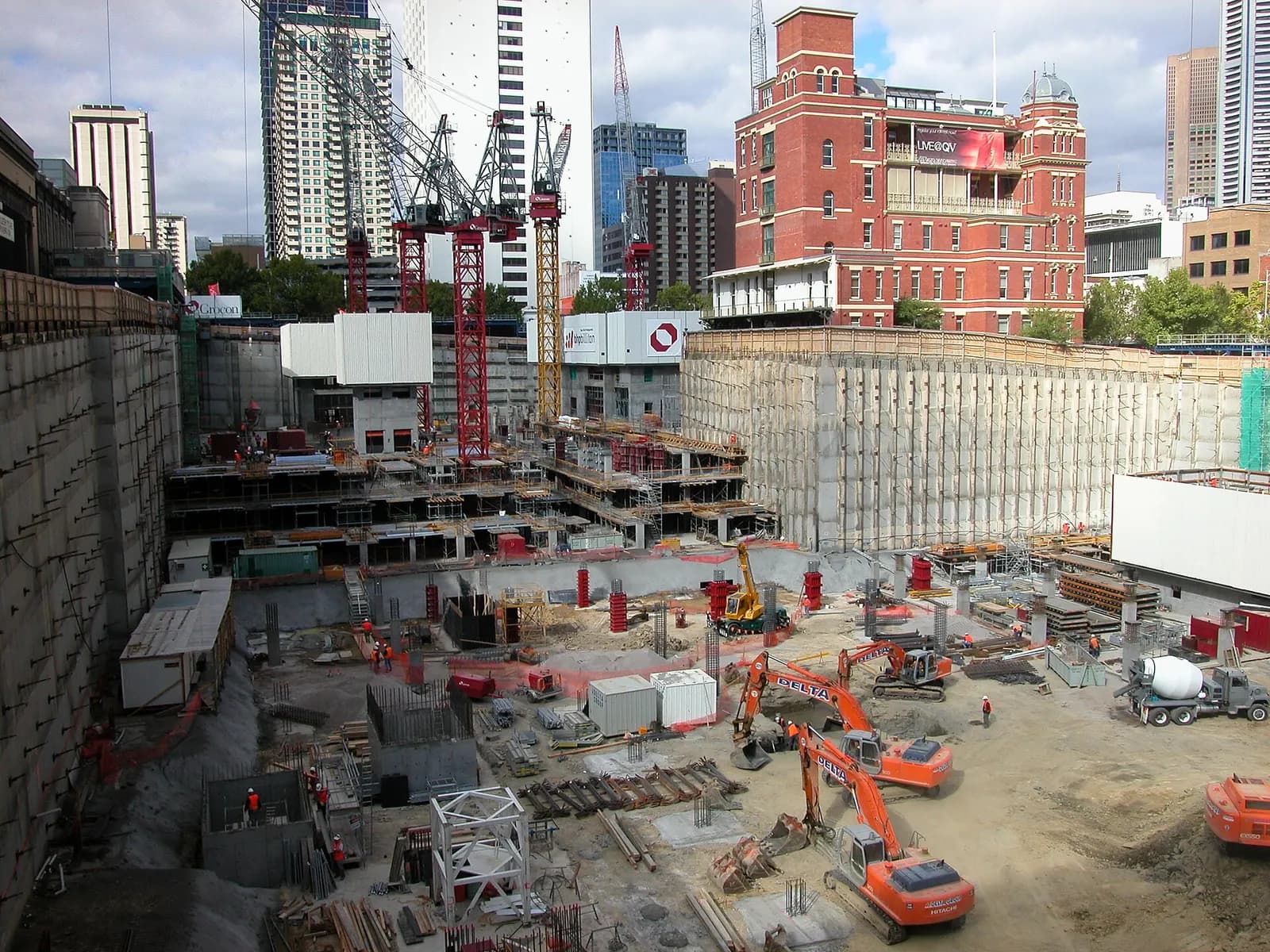 Excavators, cranes and concrete trucks working in a deep construction pit in central Melbourne