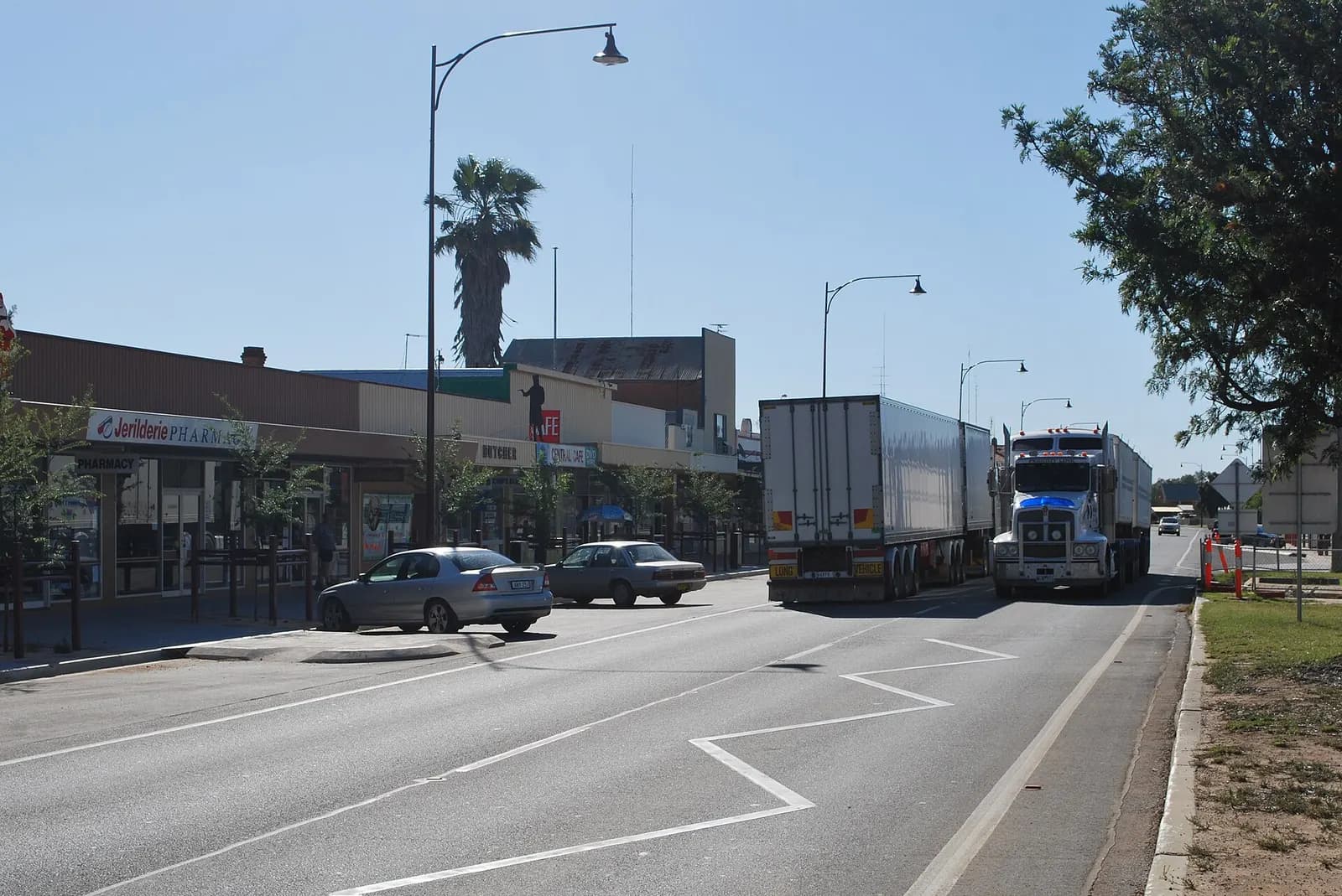 Two road-train trucks travelling along the Newell Highway through the main street of Jerilderie, NSW