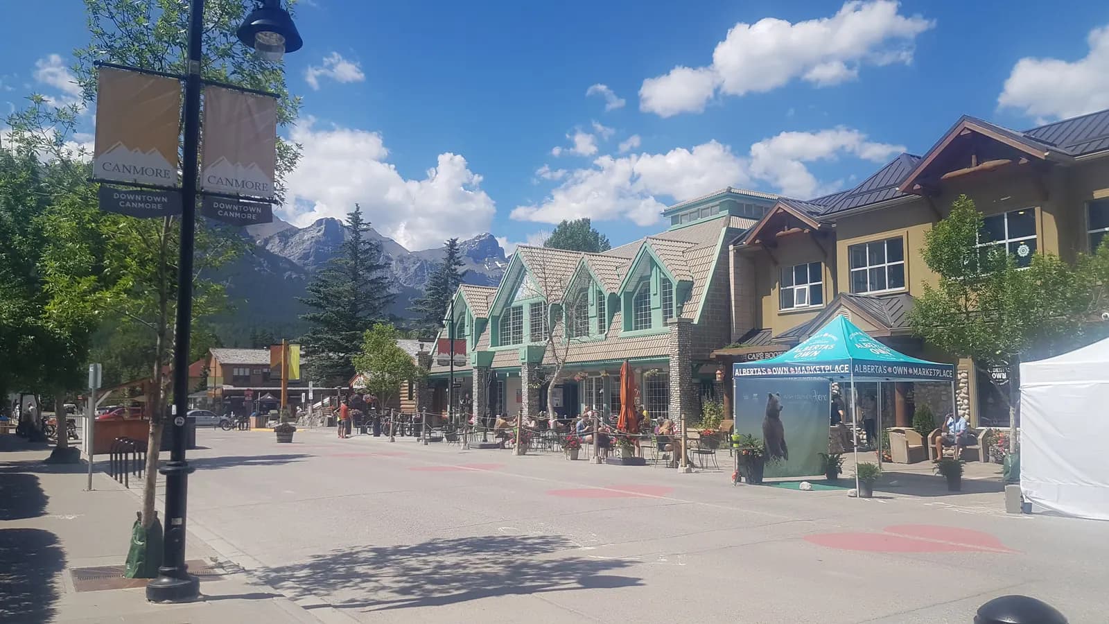 Main Street in downtown Canmore, Alberta, with shops, patios and the Rocky Mountains behind