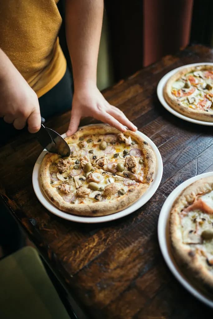 Chef in a commercial kitchen cutting a pizza fresh from the oven
