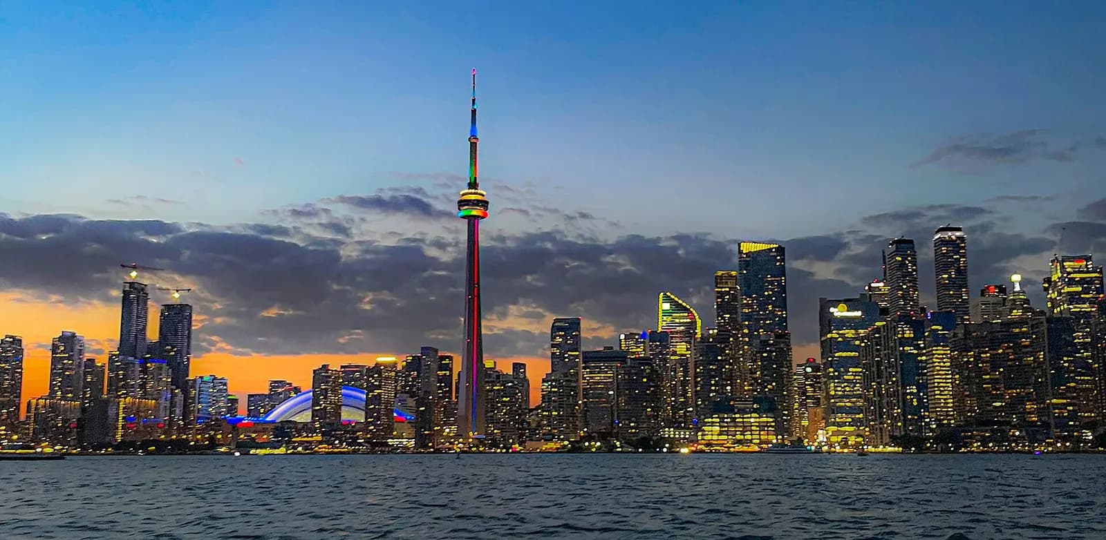 Toronto's downtown skyline and the CN Tower lit up at night across the harbour