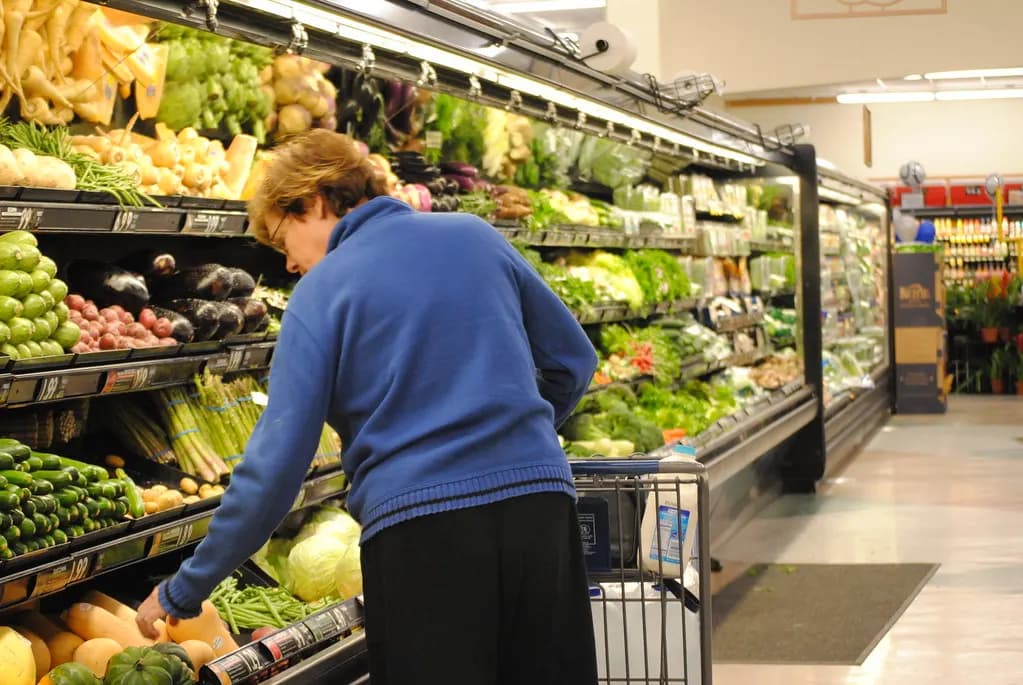 Shopper choosing vegetables from a supermarket produce aisle