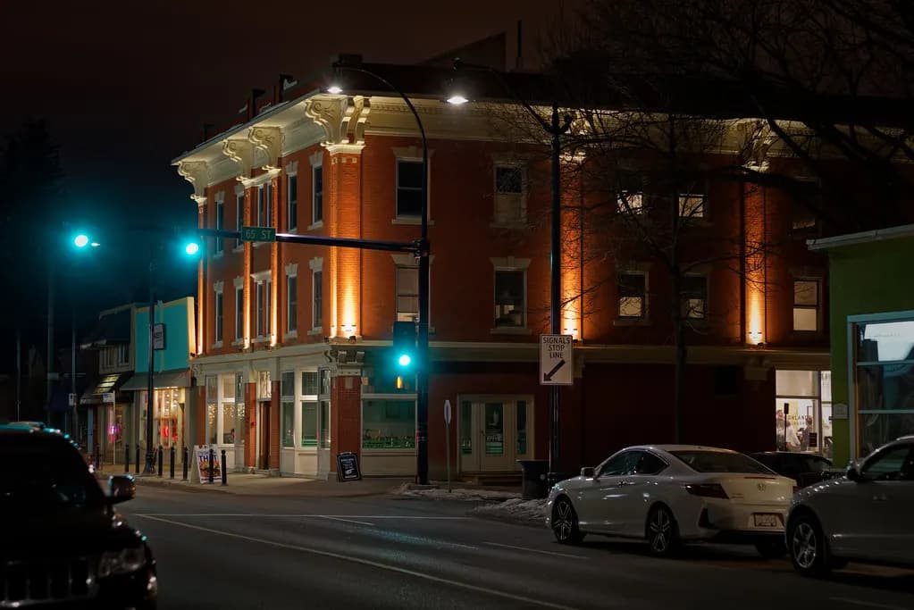 The brick Gibbard Block at night in Edmonton's Highlands neighbourhood, with ground-floor shops and apartments above