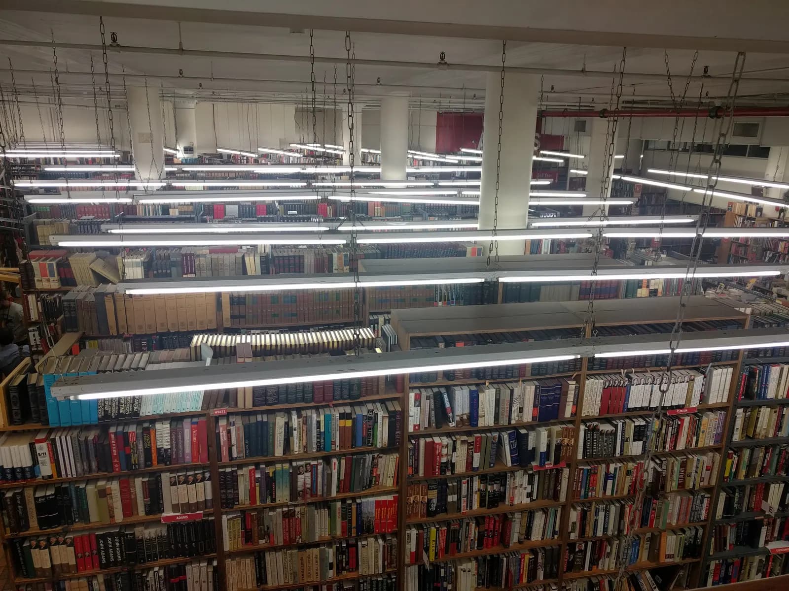 Long rows of packed bookshelves under fluorescent lights in a large bookstore