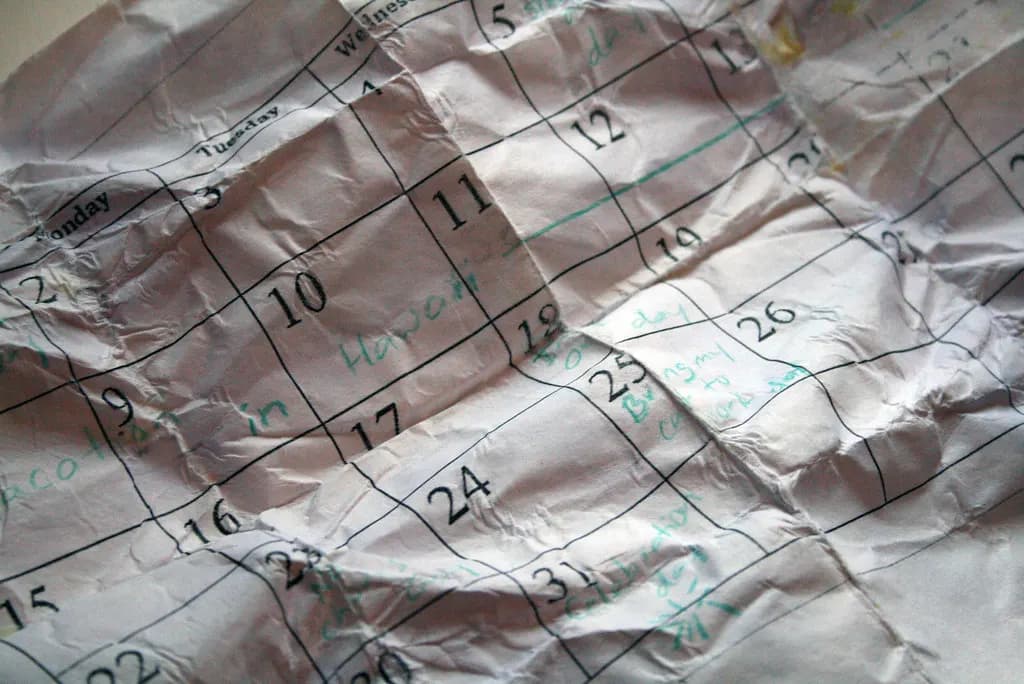 A crumpled paper calendar page with handwritten notes on several dates
