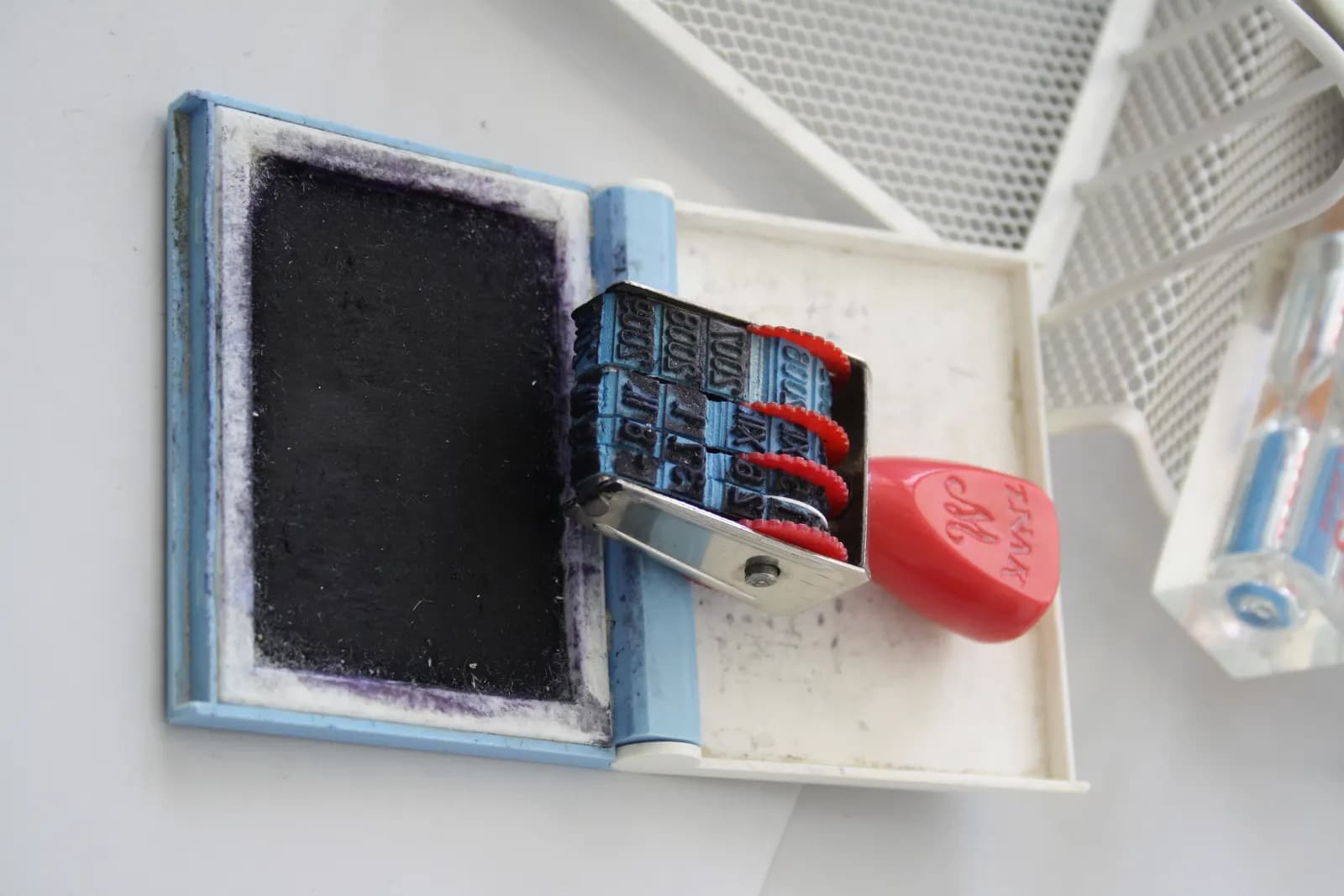 A rubber date stamp resting on an ink pad on an office desk
