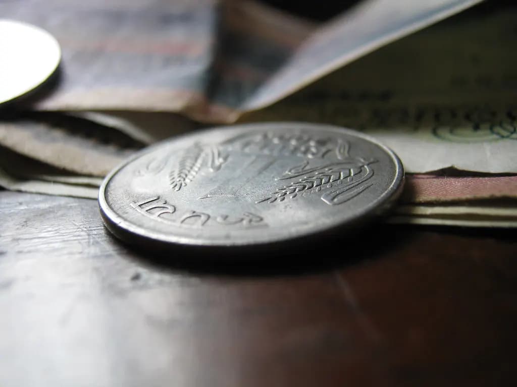 Close-up of an Indian one-rupee coin resting on folded currency notes