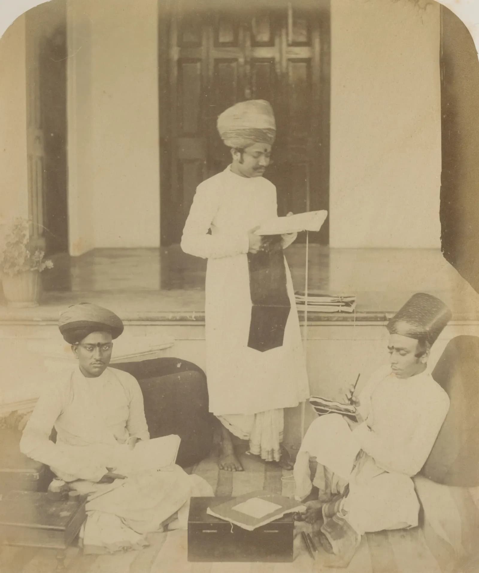 A mid-nineteenth-century photograph of three accountants with their ledgers on a verandah in Bombay